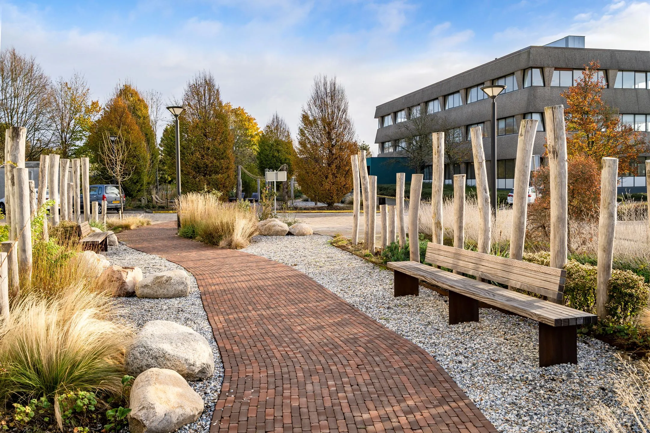Modern kantoorgebouw aan de Staverenstraat 15-17 in Deventer met een verzorgde tuin en wandelpad op de voorgrond.