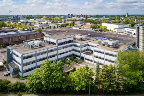 Luchtfoto van een modern kantoorpand aan de Staverenstraat 15-17 in Deventer, omgeven door groen en industriële bebouwing.