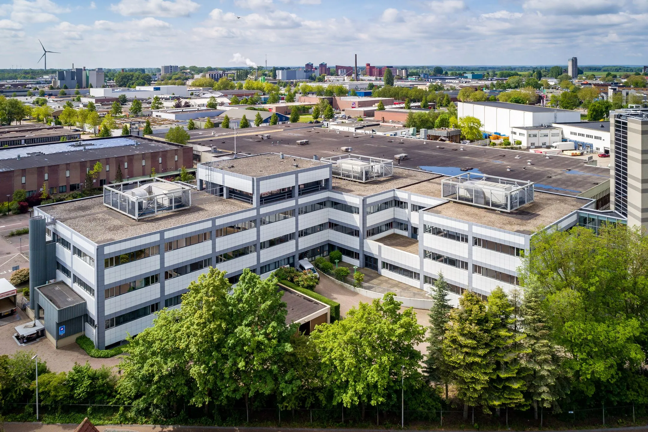 Luchtfoto van een modern kantoorpand aan de Staverenstraat 15-17 in Deventer, omgeven door groen en industriële bebouwing.