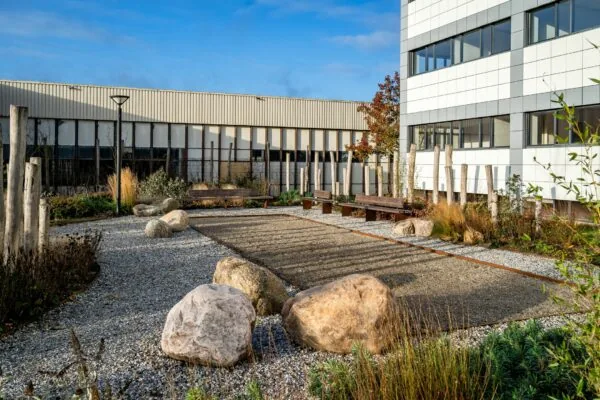 Moderne kantooromgeving aan de Staverenstraat 15-17 in Deventer met een aangelegde binnentuin met grindpaden, grote stenen en zitbanken.