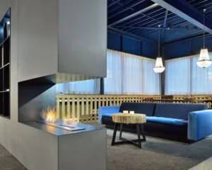 Moderne loungehoek in een kantoorruimte aan de Europalaan 2 in Den Bosch met open haard, blauwe bank en houten salontafel.