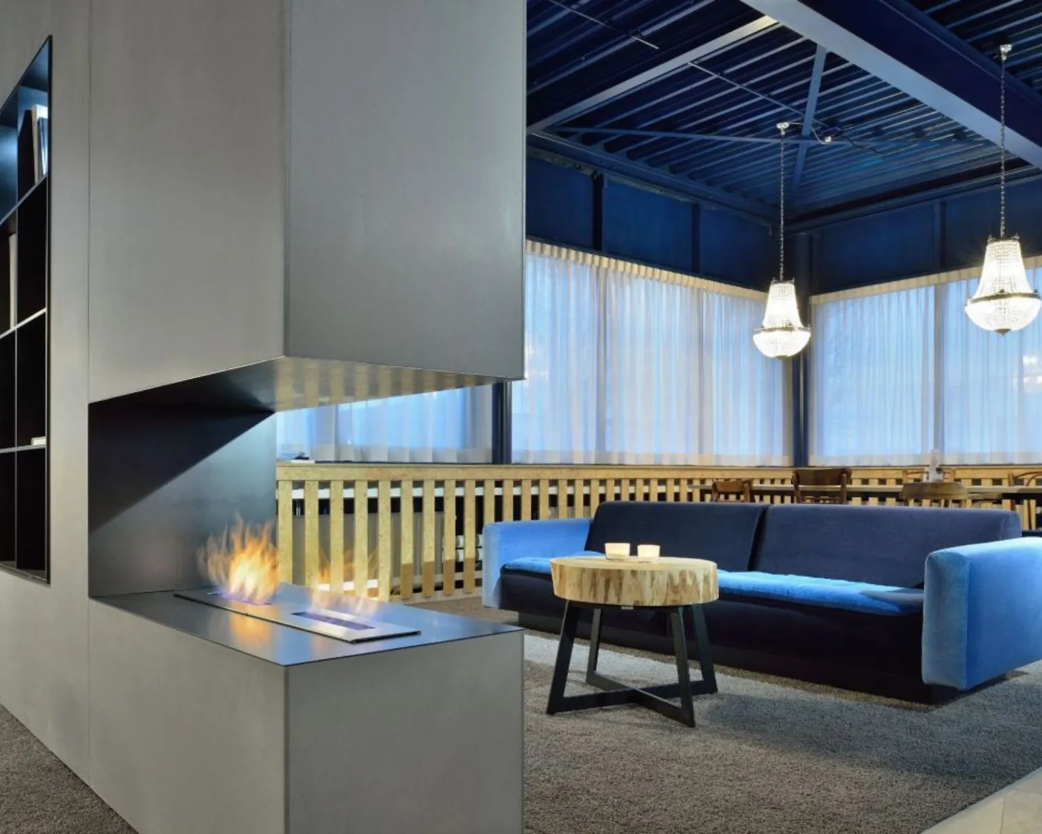 Moderne loungehoek in een kantoorruimte aan de Europalaan 2 in Den Bosch met open haard, blauwe bank en houten salontafel.