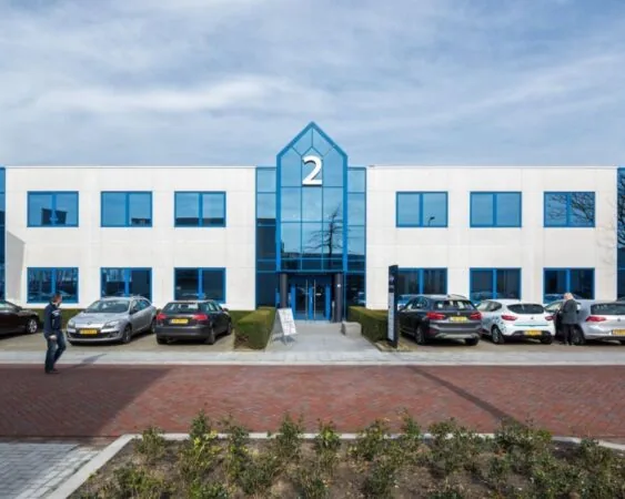 Vooraanzicht van een modern kantoorpand aan de Europalaan 2 in Den Bosch met parkeerplaatsen voor de ingang.