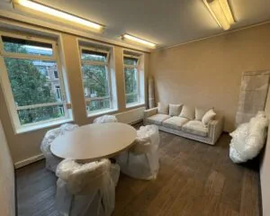 Gemeubileerde kantoorruimte met ronde tafel, stoelen en bank aan de Frans van Mierisstraat 50d in Amsterdam.