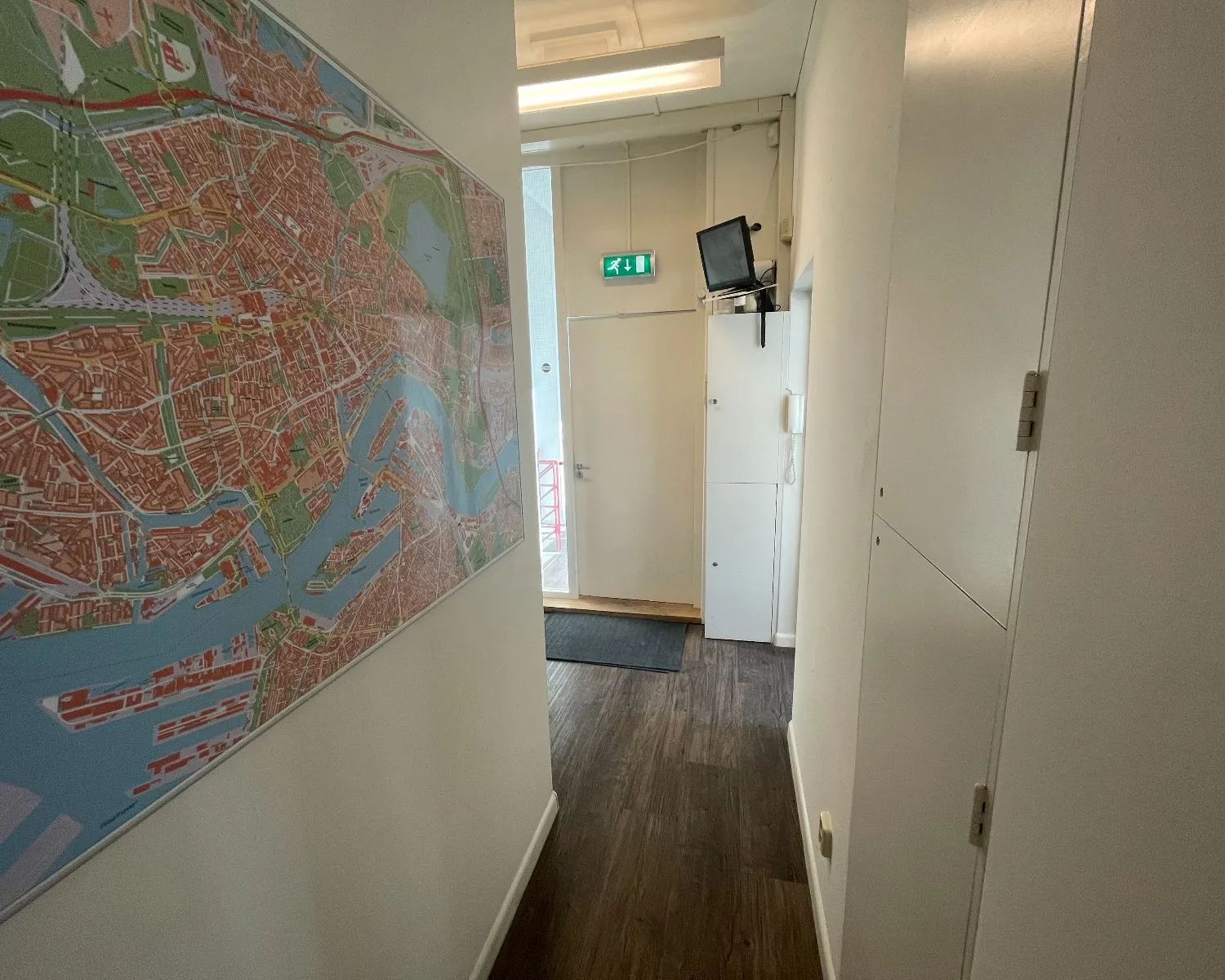 Hal van een kantoorruimte aan de Frans van Mierisstraat 50d in Amsterdam met een grote wandkaart en houten vloer.