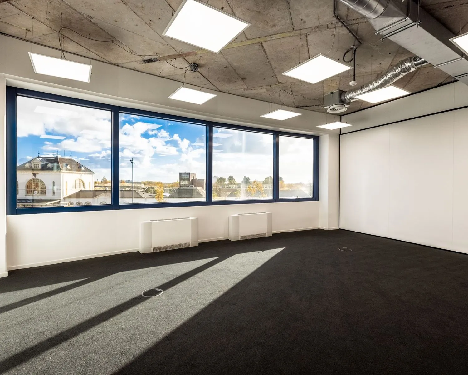 Lichte, moderne kantoorruimte met groot raam en uitzicht op het centrum van Leeuwarden aan de Lange Marktstraat.