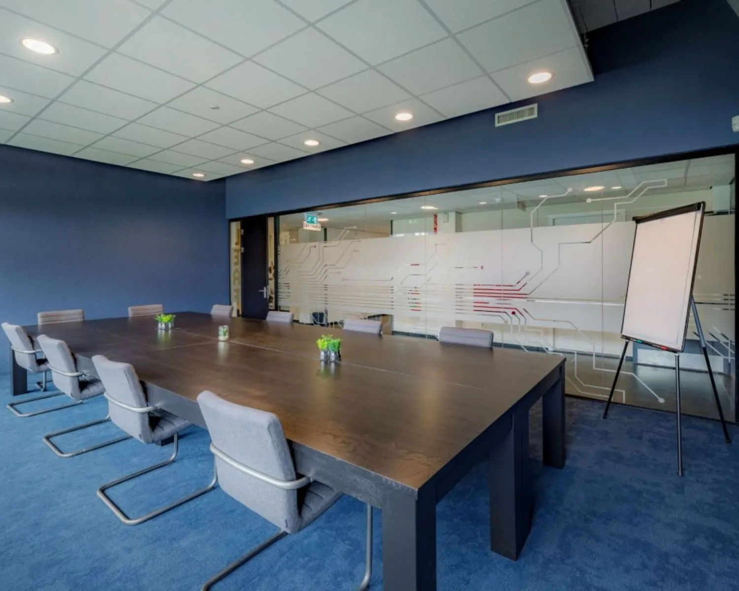 Moderne vergaderruimte met grote tafel, stoelen, flipover en glazen wand in een kantoor aan de Oude Apeldoornseweg in Apeldoorn.