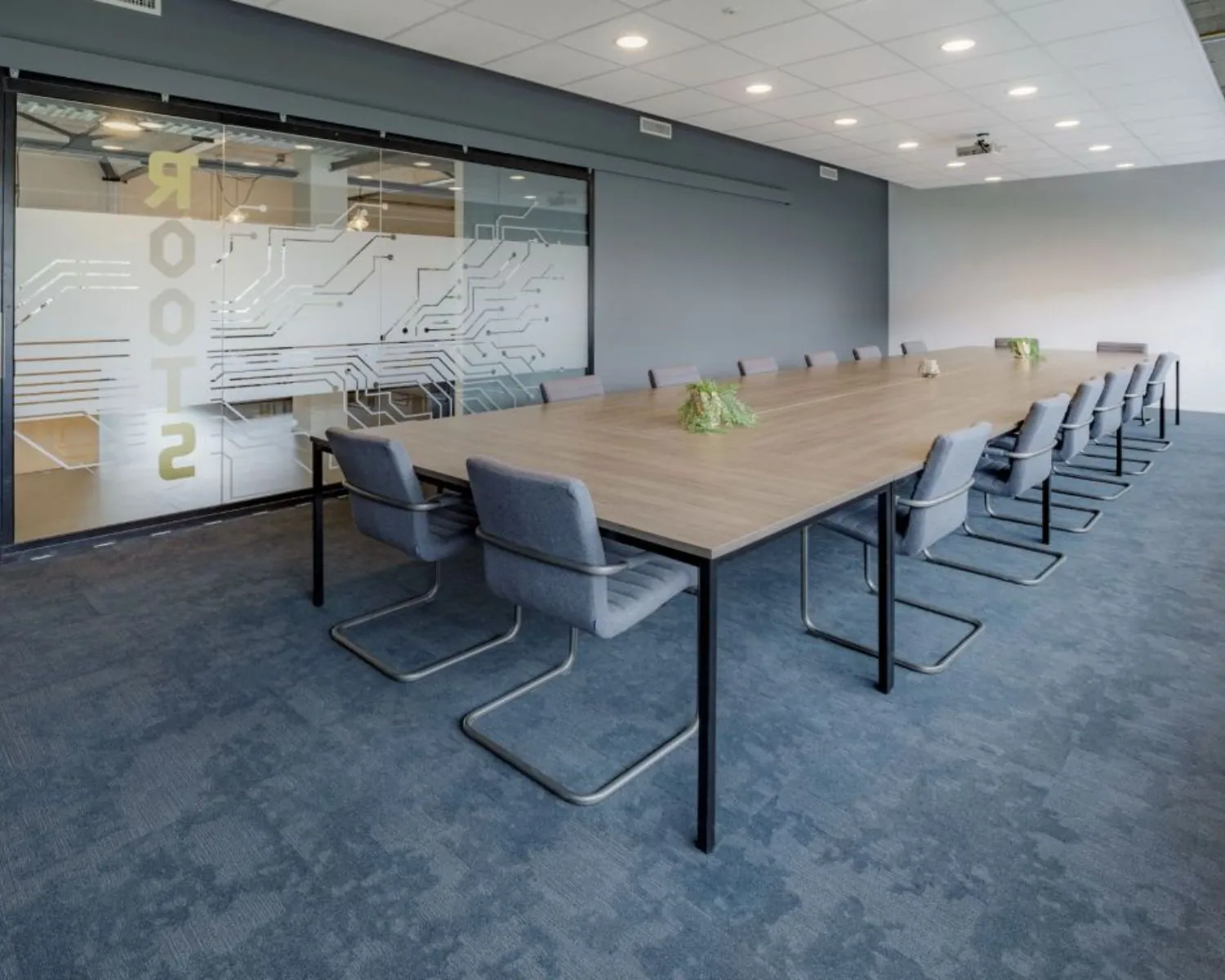 Moderne vergaderruimte met een lange houten tafel, grijze stoelen en glazen wand in een kantoorpand aan de Oude Apeldoornseweg in Apeldoorn.