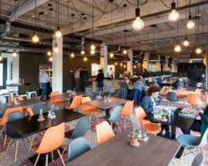 Moderne bedrijfsrestaurant met kleurrijke stoelen en sfeerverlichting in een kantoorruimte aan de Oude Apeldoornseweg 41-45 in Apeldoorn.