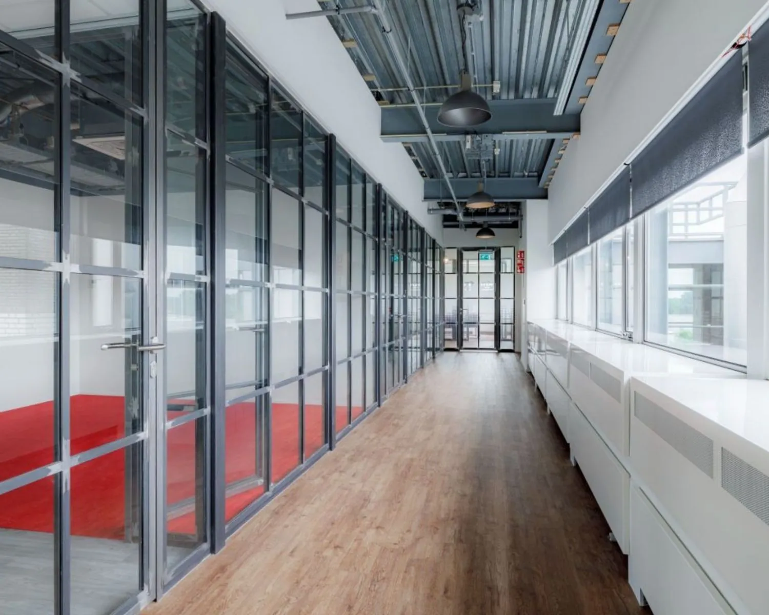 Moderne gang met glazen kantoorwanden en houten vloer in een kantoorgebouw aan de Oude Apeldoornseweg 41-45 in Apeldoorn.