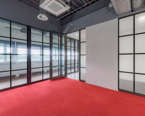 Moderne kantoorruimte met glazen wanden en rode vloerbedekking aan de Oude Apeldoornseweg 41-45 in Apeldoorn.