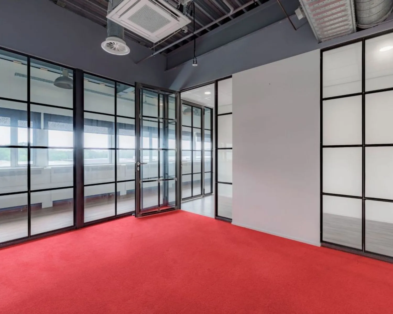 Moderne kantoorruimte met glazen wanden en rode vloerbedekking aan de Oude Apeldoornseweg 41-45 in Apeldoorn.