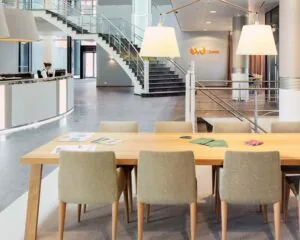 Moderne entreehal van kantoorruimte in het WTC Almere met receptiebalie, vergadertafel en trap naar boven.