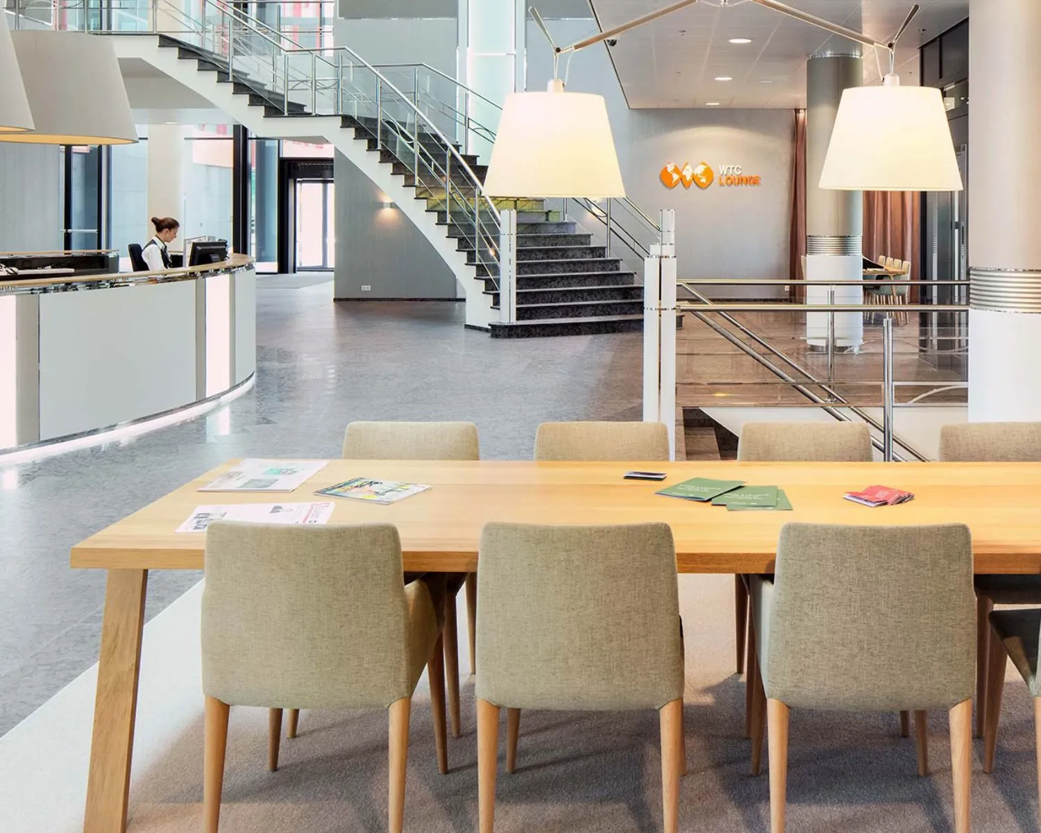 Moderne entreehal van kantoorruimte in het WTC Almere met receptiebalie, vergadertafel en trap naar boven.