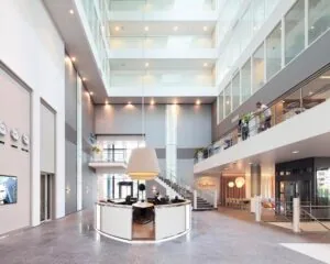 Moderne, lichte entreehal van het WTC-gebouw aan de PJ Oudweg 4 in Almere met een ronde receptiebalie en glazen wanden.