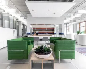 Moderne kantoorruimte op het Piet Mondriaanplein met groene zitbanken, een grote plant en een open keuken in kleurrijke tegels.