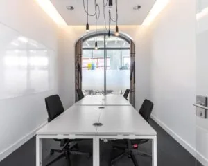 Moderne kantoorruimte met vier werkplekken, witte tafels en glazen deur aan het Piet Mondriaanplein 13.