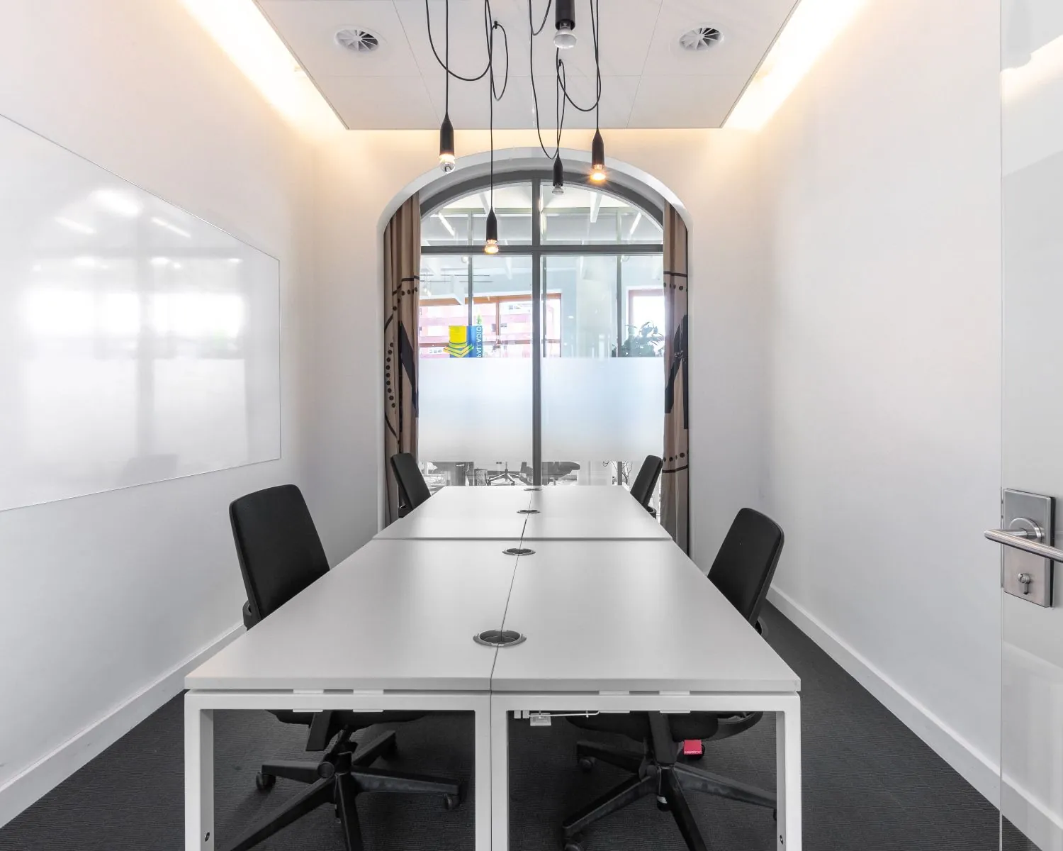 Moderne kantoorruimte met vier werkplekken, witte tafels en glazen deur aan het Piet Mondriaanplein 13.