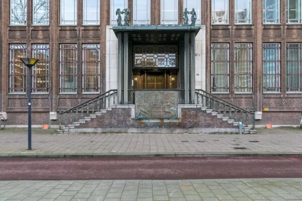 Monumentale entree van het kantoorgebouw aan Blaak 34 in Rotterdam met brede trap en decoratief reliëf.