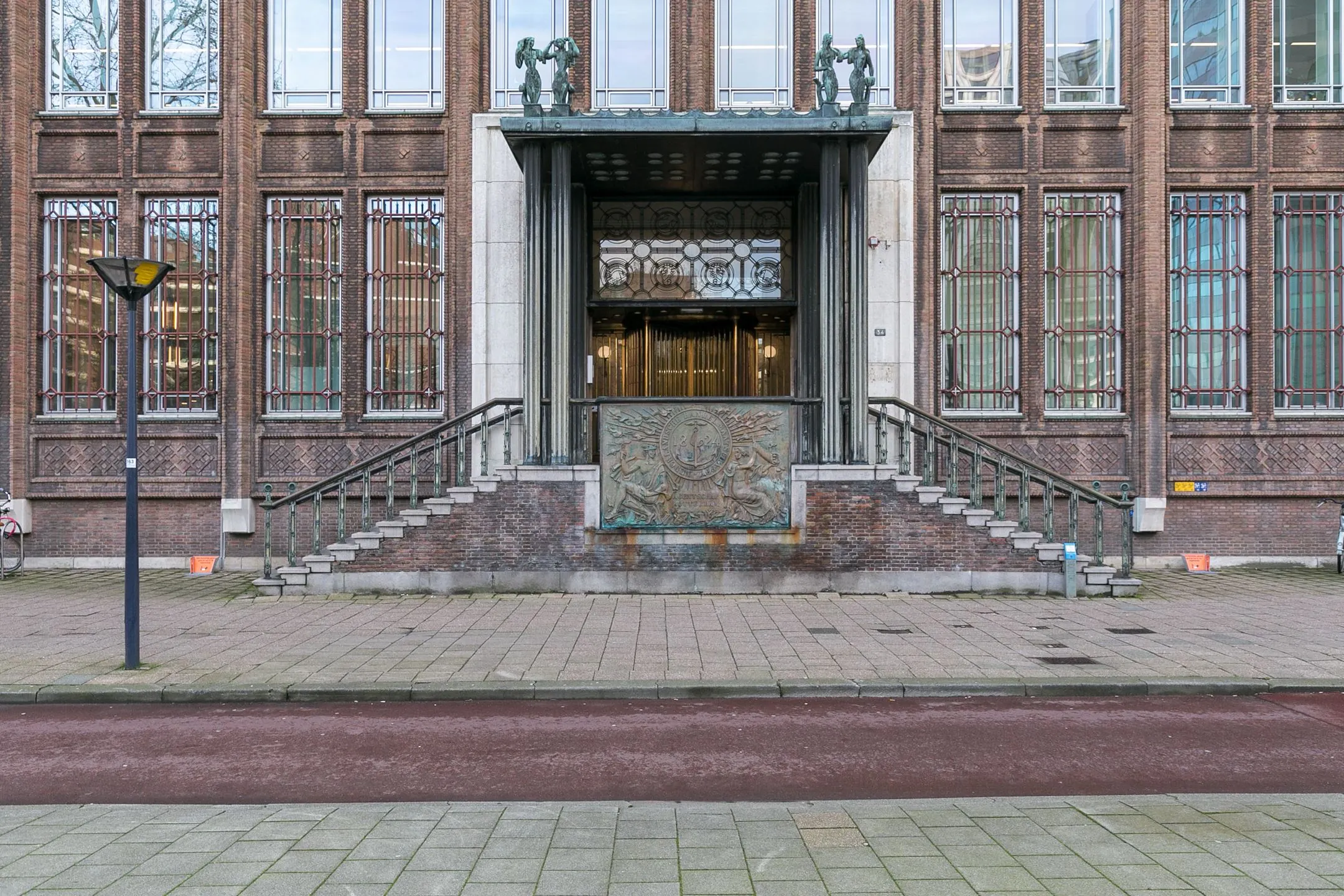 Monumentale entree van het kantoorgebouw aan Blaak 34 in Rotterdam met brede trap en decoratief reliëf.