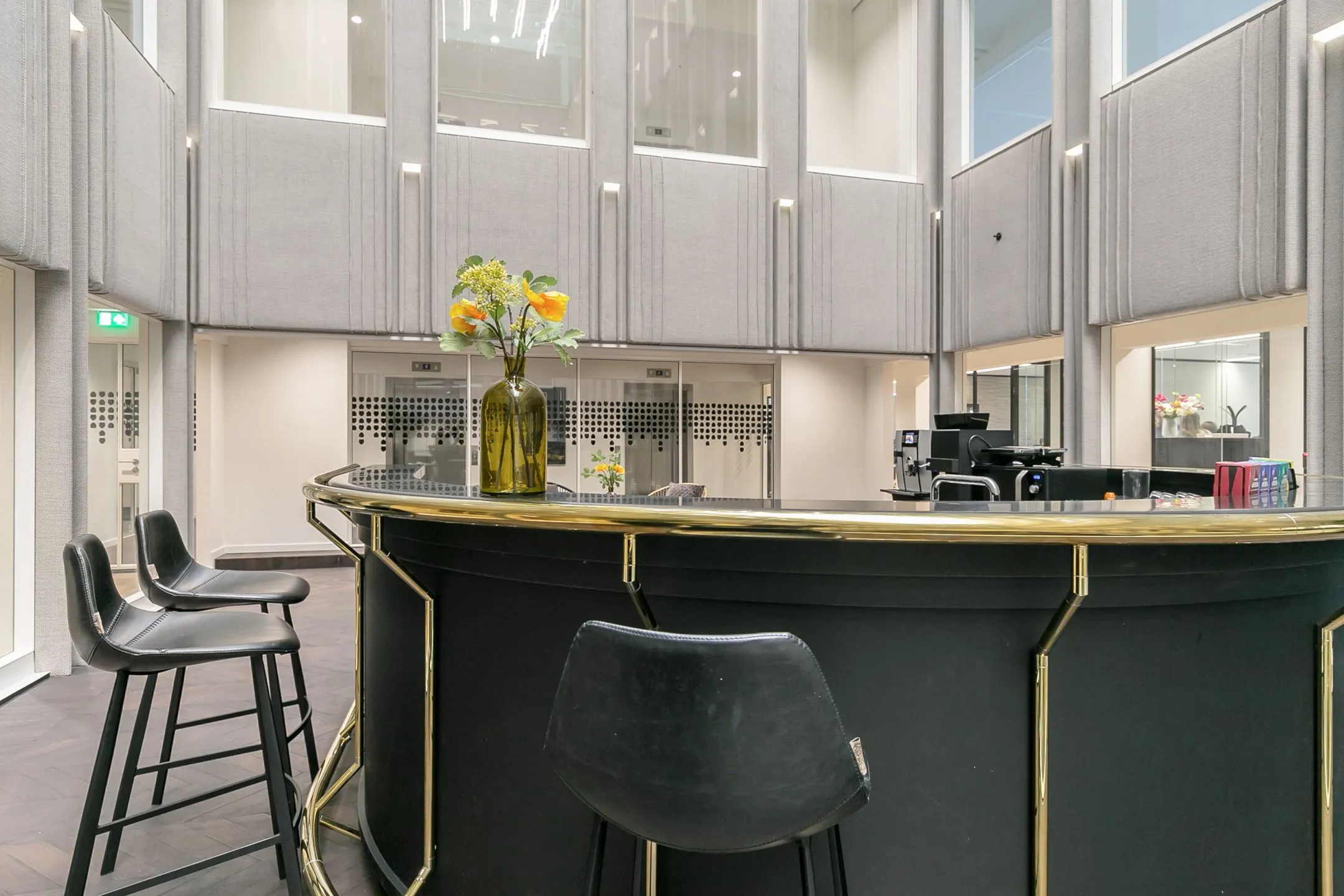 Moderne ontvangstbalie met hoge stoelen en bloemenvaas in kantoorruimte aan Rotterdam Blaak 34.