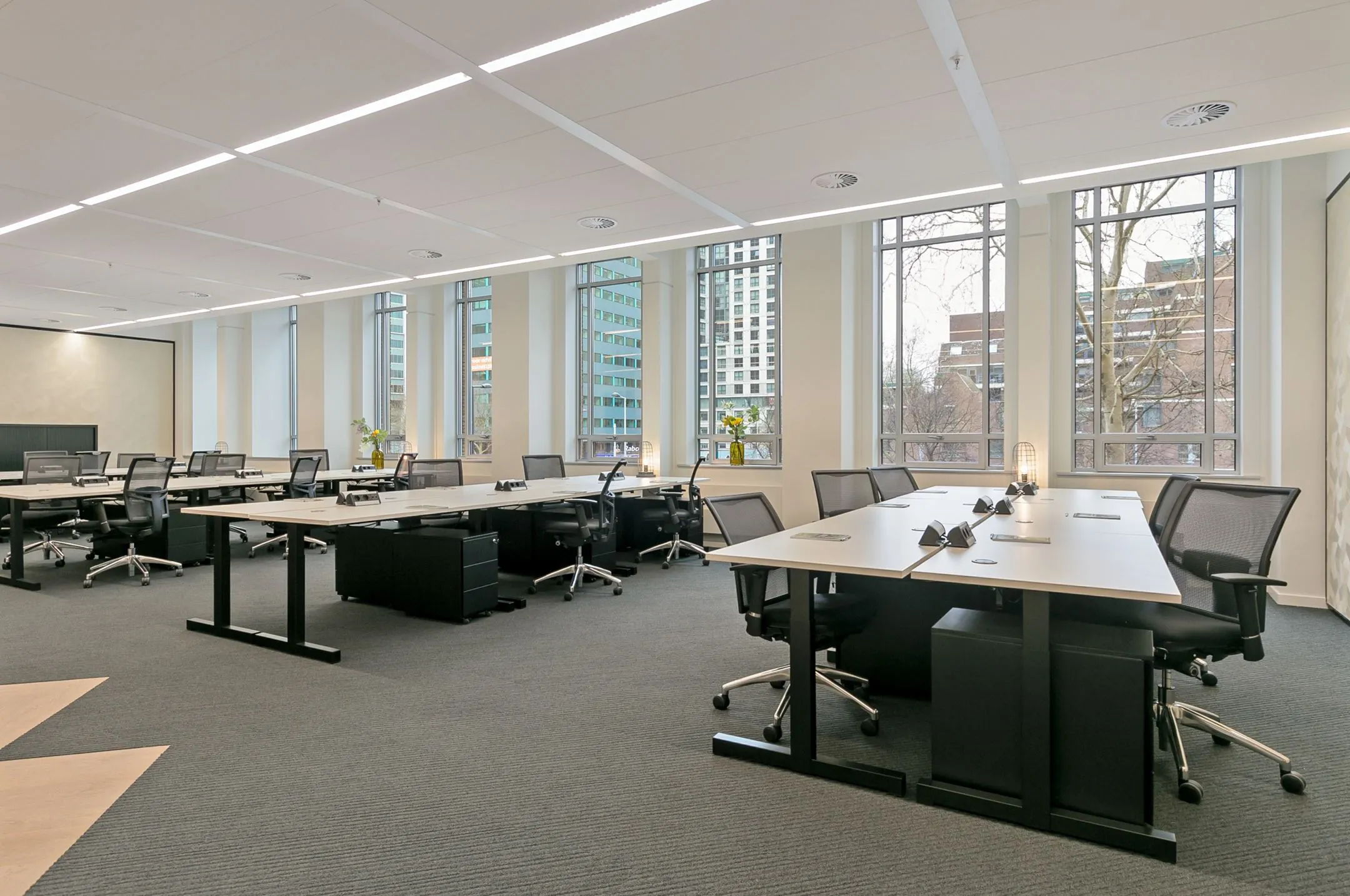 Moderne kantoorruimte met meerdere werkplekken en grote ramen aan de Blaak 34 in Rotterdam.
