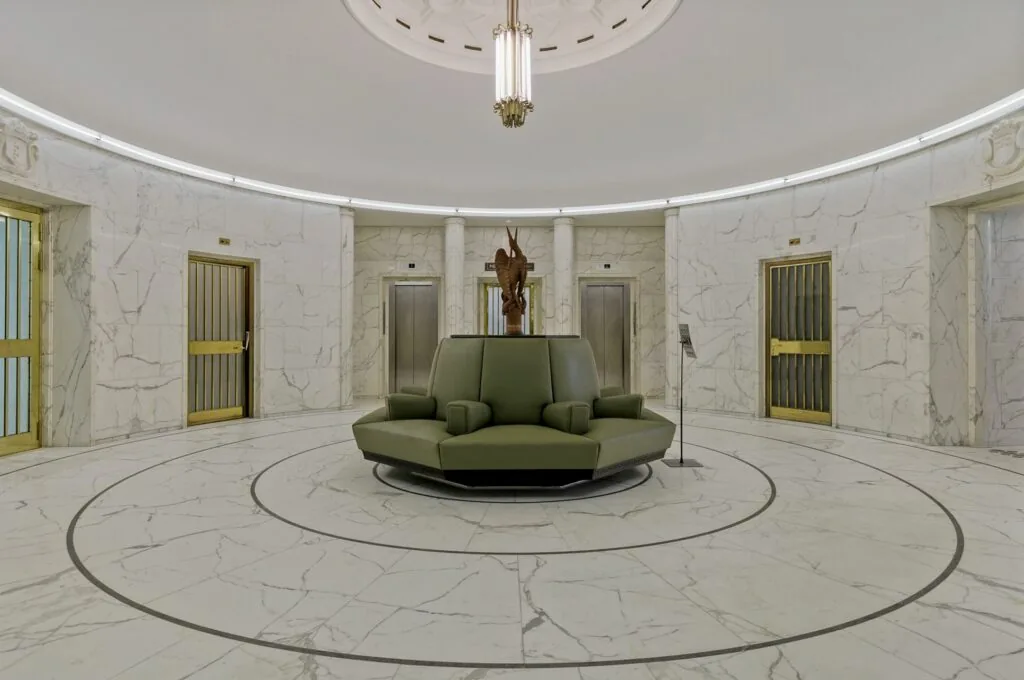 Ronde marmeren ontvangsthal met groene zitbank en liften in kantoorgebouw Blaak 34 in Rotterdam.
