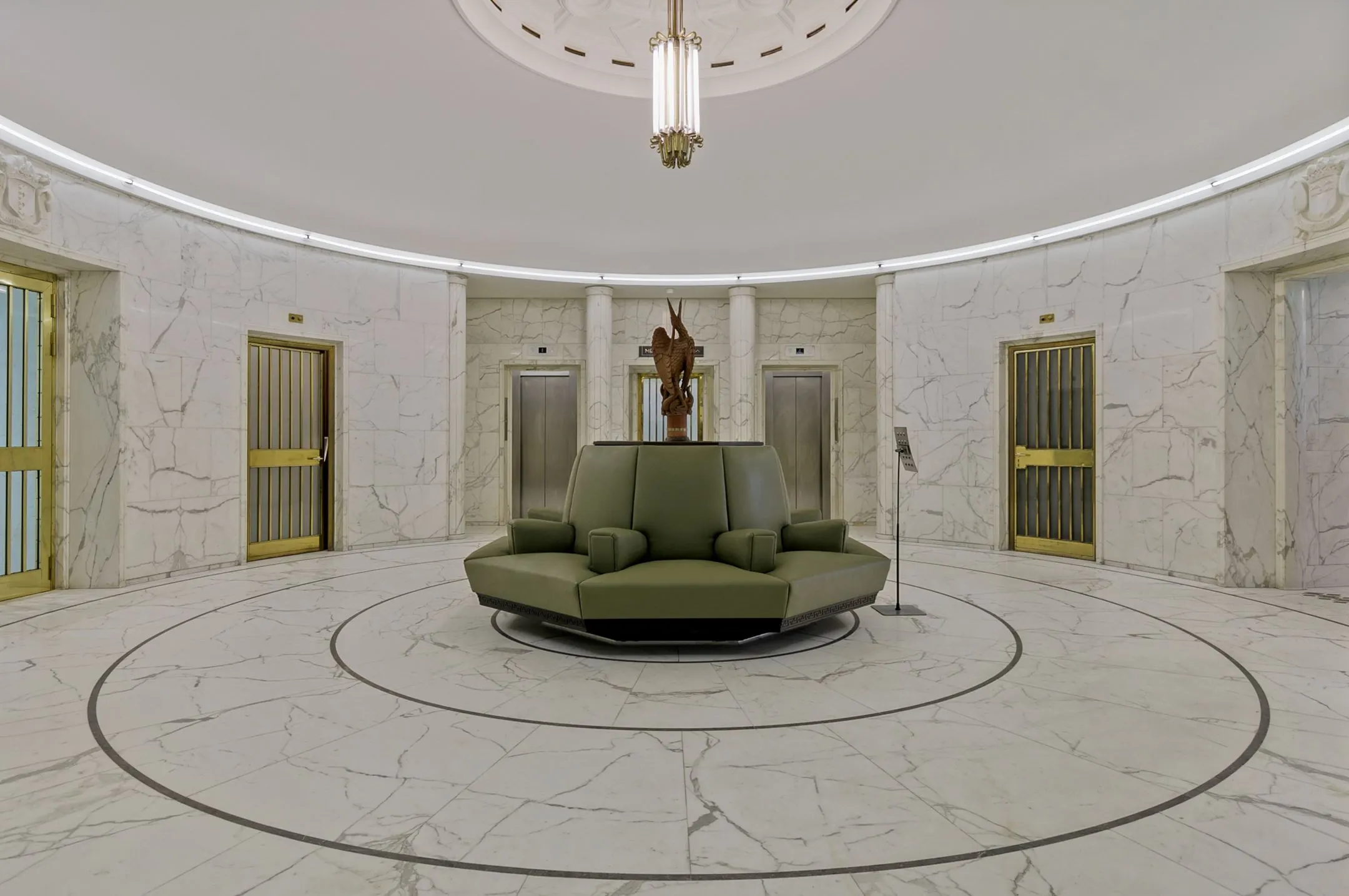 Ronde marmeren ontvangsthal met groene zitbank en liften in kantoorgebouw Blaak 34 in Rotterdam.