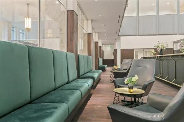 Stijlvolle wachtruimte met donkergroene banken en zwarte fauteuils in kantoorruimte Rotterdam Blaak 34.