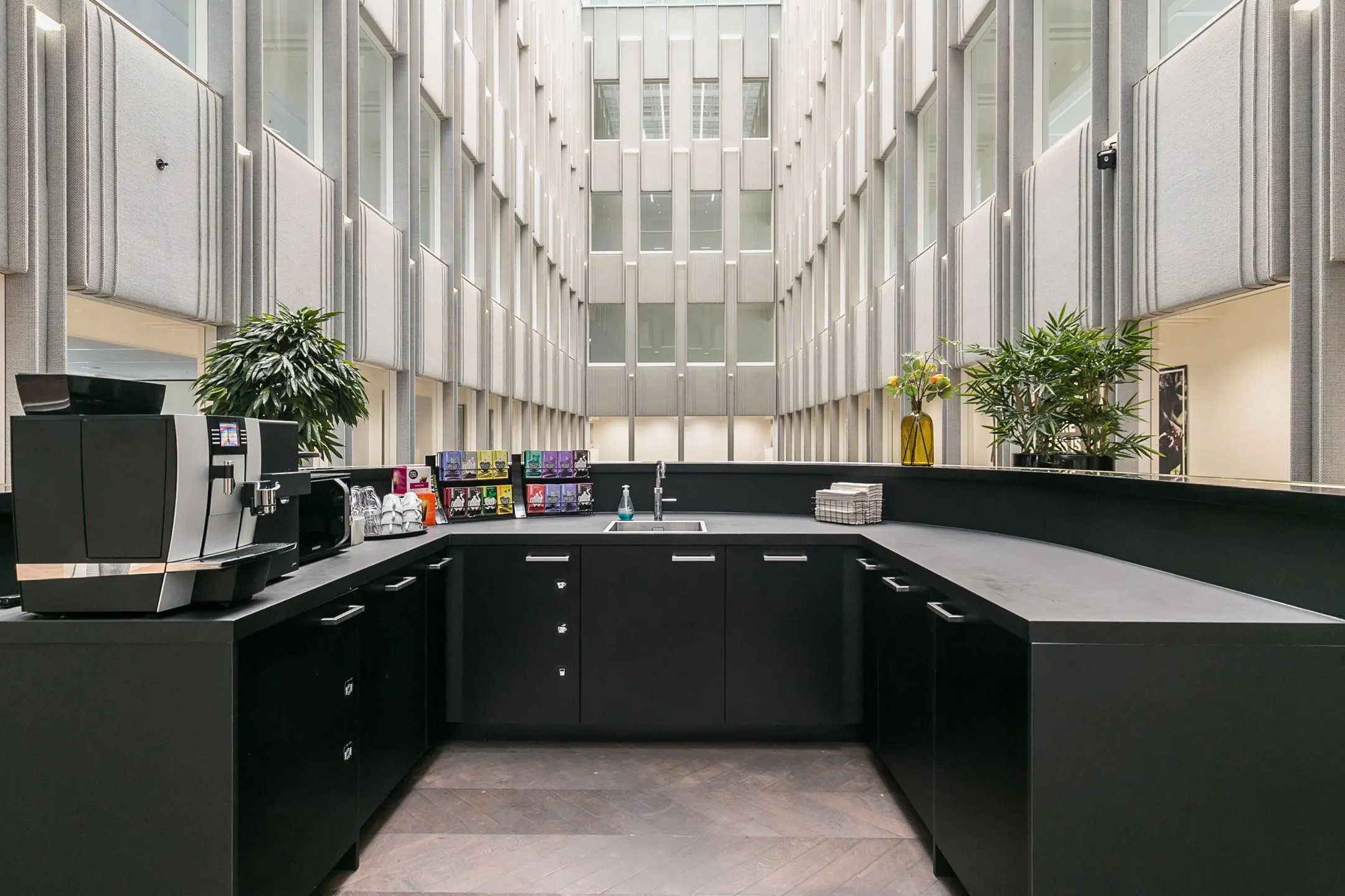 Moderne koffiekeuken met koffieautomaat en theeselectie in een atrium van kantoorpand Blaak 34 in Rotterdam.