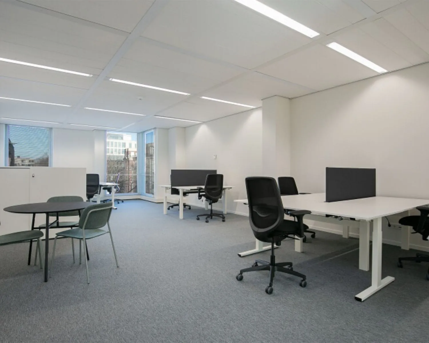 Moderne, lichte kantoorruimte met bureaus en vergadertafel aan het Alexanderveld in Den Haag.