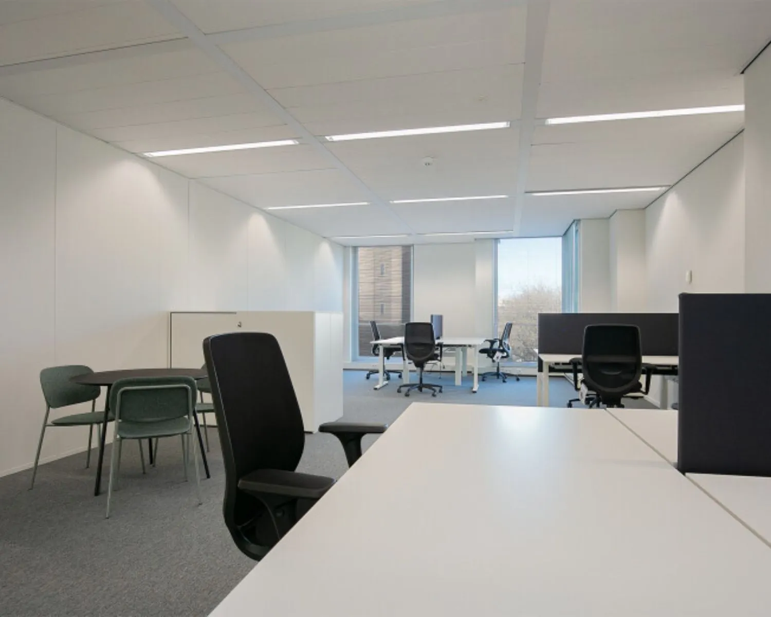 Moderne en lichte kantoorruimte met bureaus, stoelen en vergadertafel aan het Alexanderveld 5 in Den Haag.