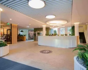 Moderne en lichte entreehal van een kantoorpand aan het Alexanderveld 5 in Den Haag met een ronde receptiebalie en veel groen.