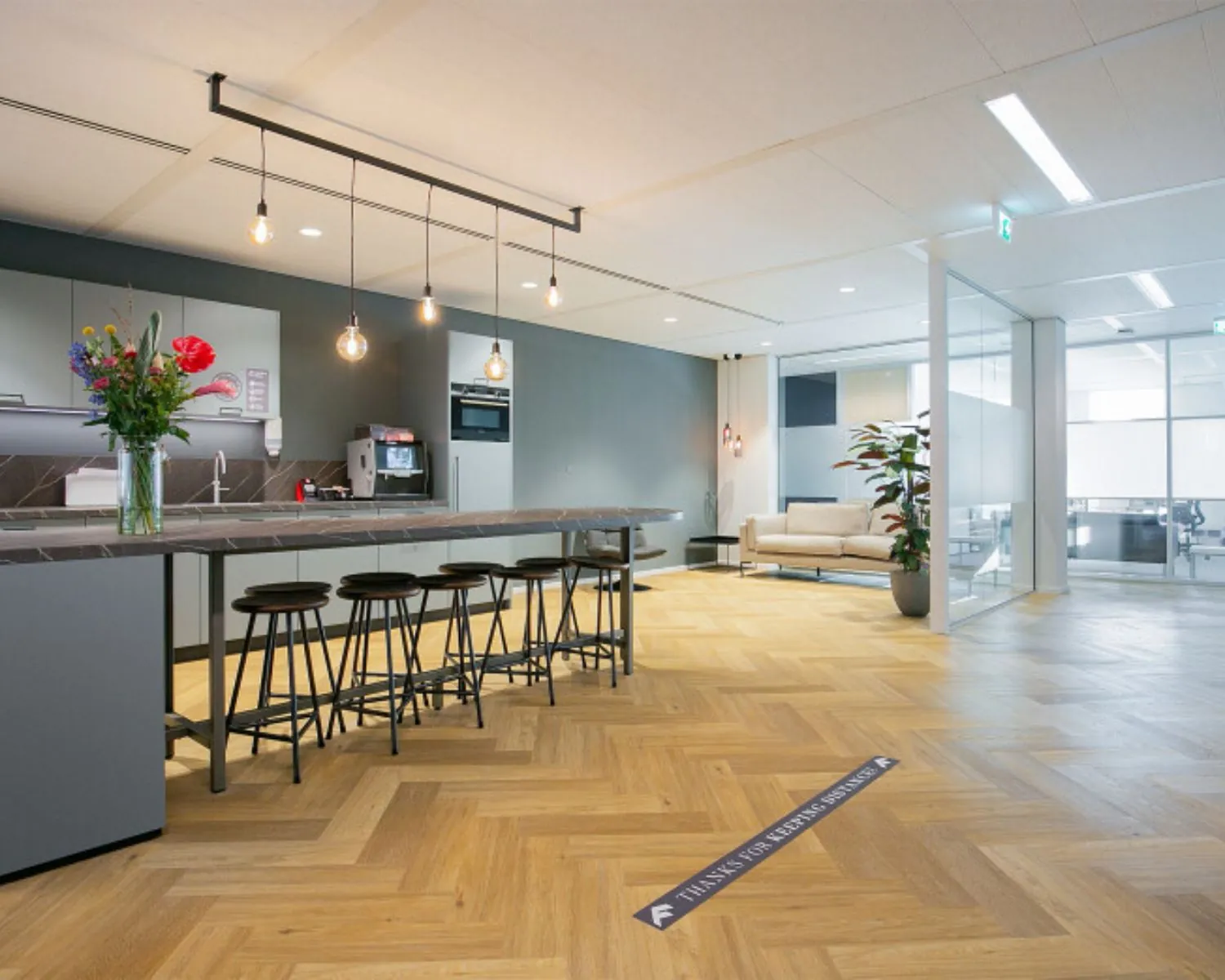 Moderne kantoorruimte in Den Haag met open keuken, barzitjes, zithoek en glazen vergaderruimtes.