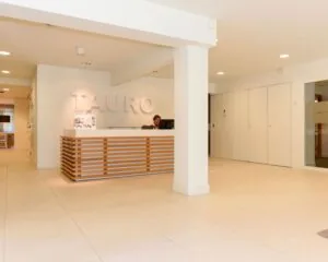 Moderne receptieruimte van kantoorruimte Tauro aan de Herenweg 15 in Heemstede met een balie en een medewerker achter een computer.