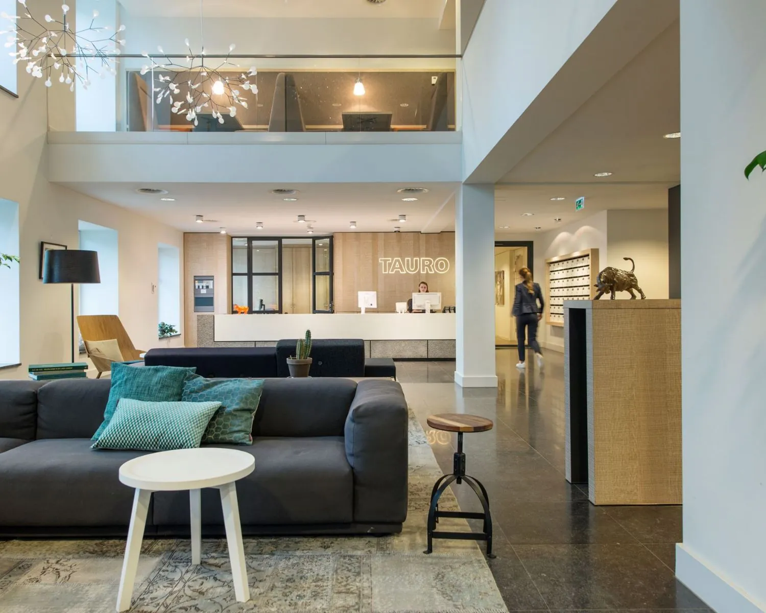 Moderne ontvangstruimte van kantoorpand Tauro aan de Koninginnegracht 19 in Den Haag met balie, zithoek en decoratieve verlichting.