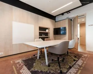 Moderne vergaderruimte in een kantoor aan de Koninginnegracht 19 in Den Haag met een witte tafel, designstoelen, flatscreen en wandkast.