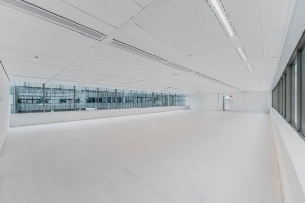 Lichte, lege kantoorruimte met grote ramen aan de Herikerbergweg in Amsterdam.