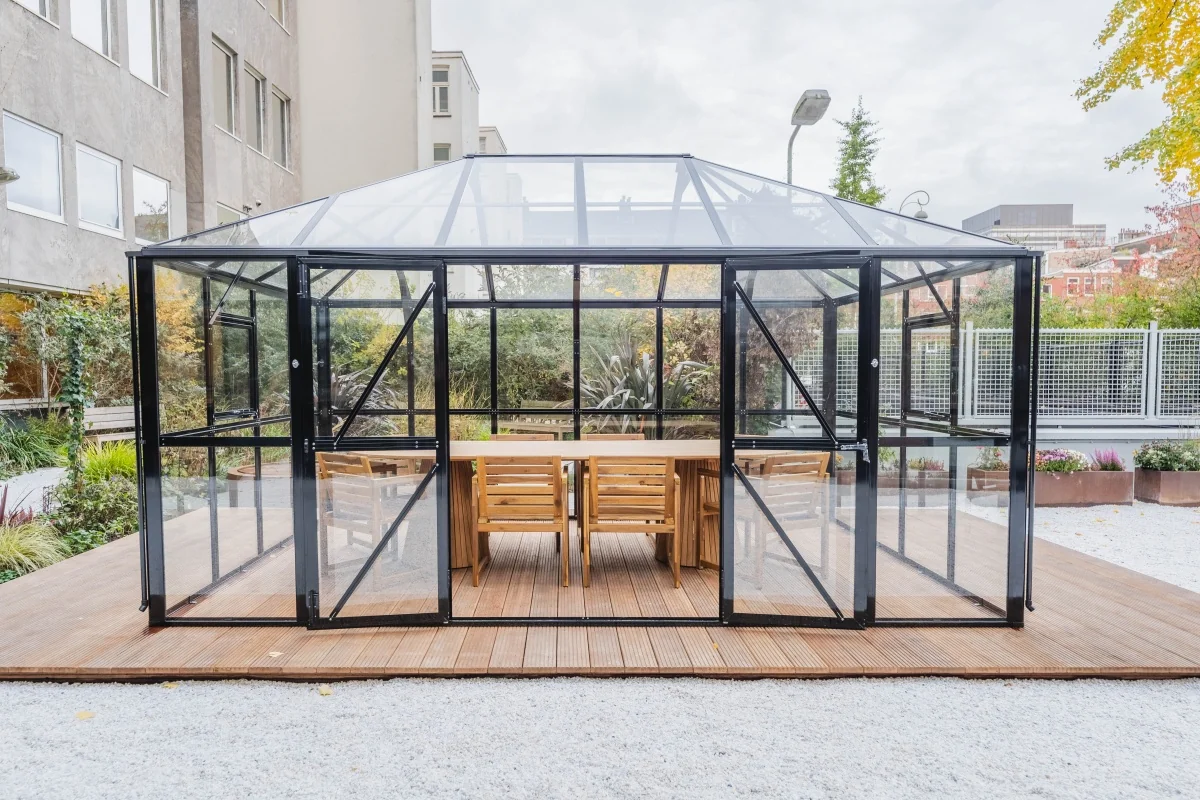 Glazen vergaderruimte met houten tafel en stoelen op het buitenterrein van een kantoorpand aan de Weesperstraat in Amsterdam.