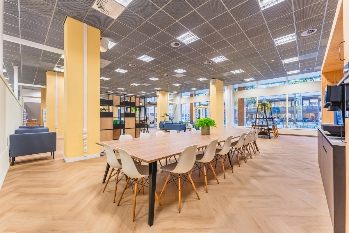 Moderne, open kantoorruimte aan de Weesperstraat in Amsterdam met een lange vergadertafel, grote ramen en veel natuurlijk licht.