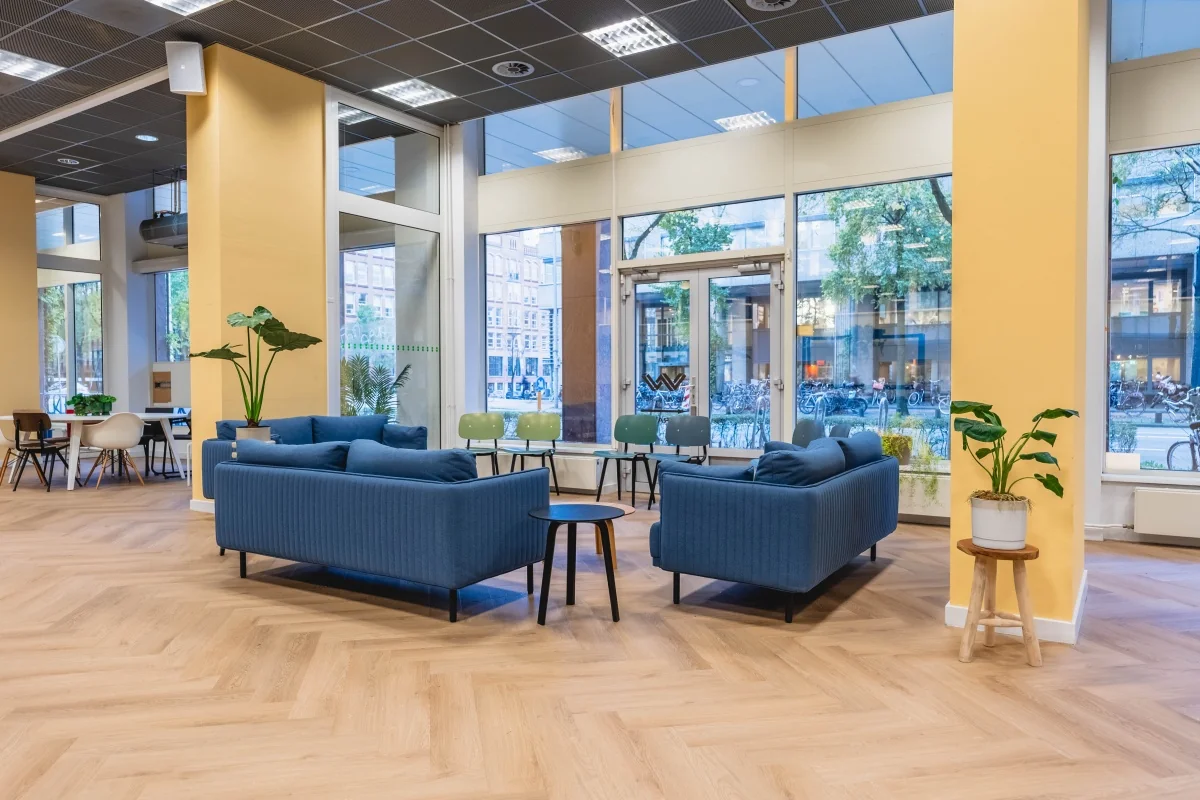 Moderne, open kantoorruimte met blauwe zitbanken en grote ramen aan de Weesperstraat 107-121 in Amsterdam.