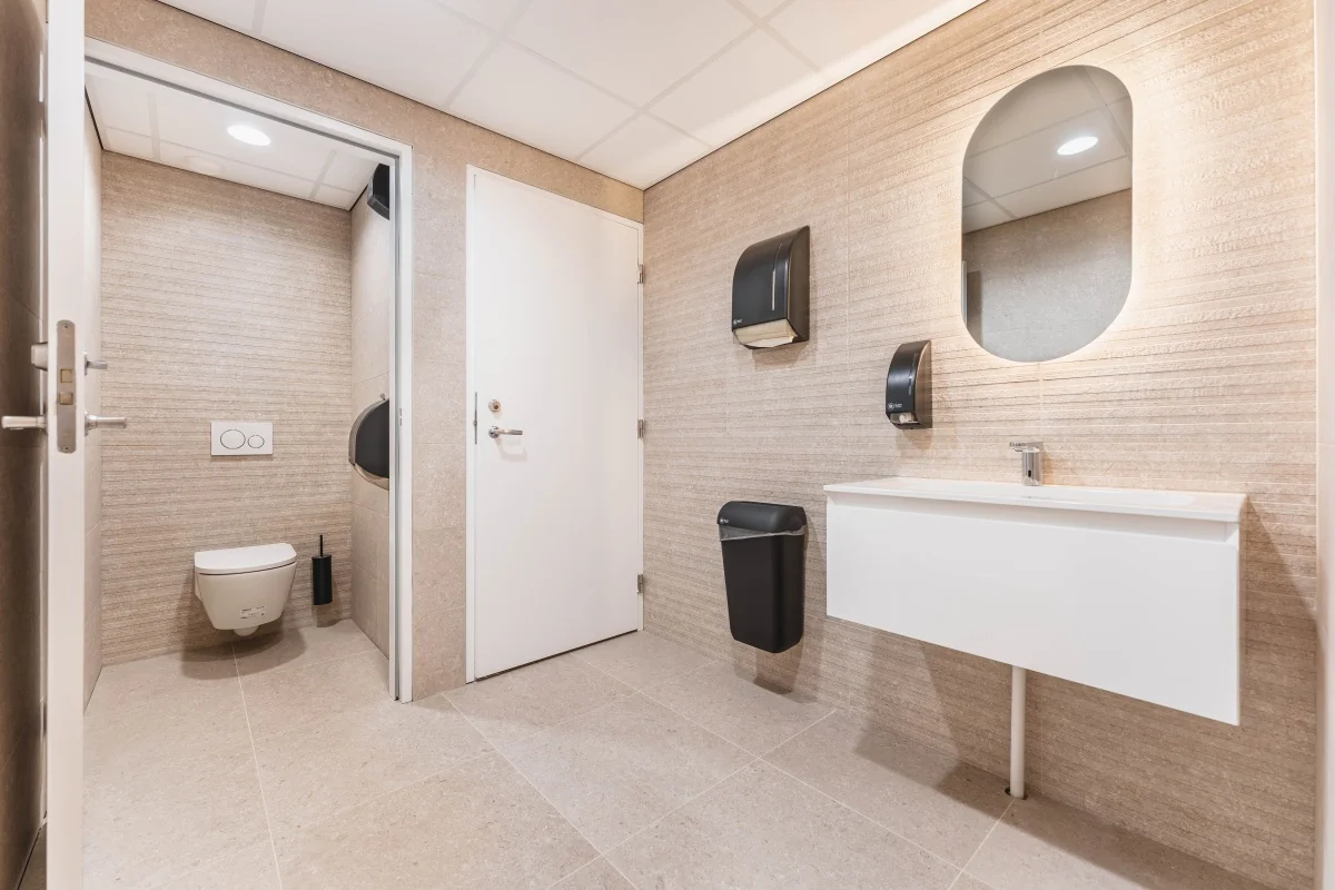 Moderne toiletruimte in een kantoor aan de Weesperstraat in Amsterdam met wastafel, spiegel en toilet.