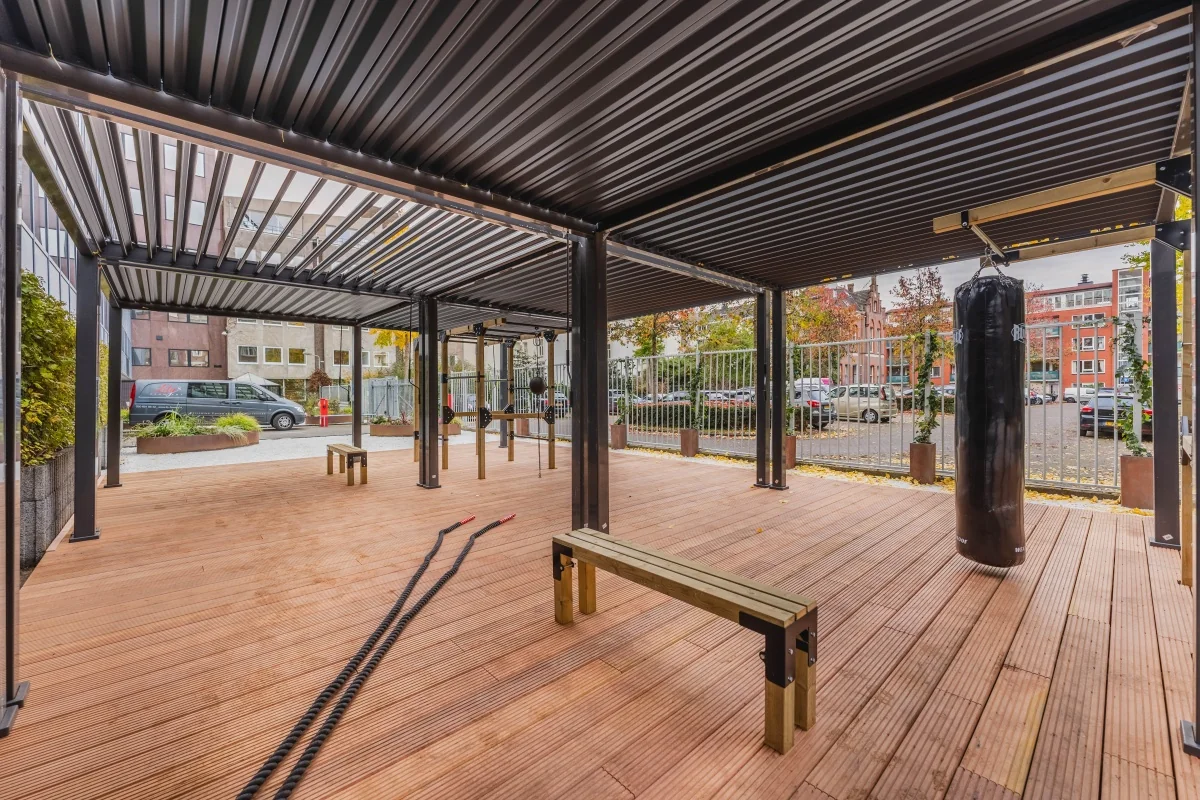 Overdekte buitensportplek met fitnessapparatuur, bokszak en houten vloer bij Weesperstraat 107-121 in Amsterdam.