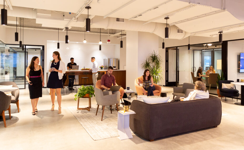 Moderne en sfeervolle kantoorruimte aan het Burgerweeshuispad 301 in Amsterdam met mensen in gesprek en aan het werk in een open loungegedeelte.