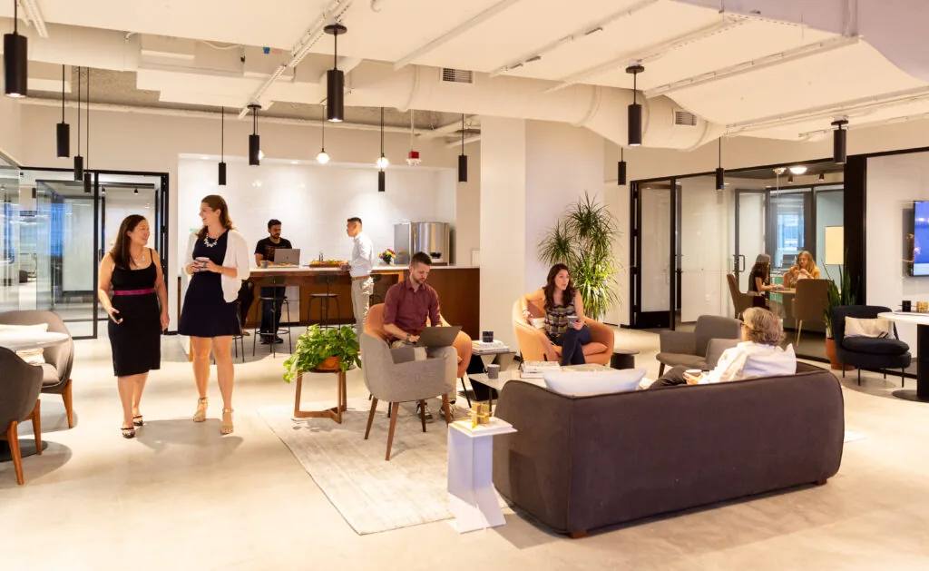 Moderne en sfeervolle kantoorruimte aan het Burgerweeshuispad 301 in Amsterdam met mensen in gesprek en aan het werk in een open loungegedeelte.