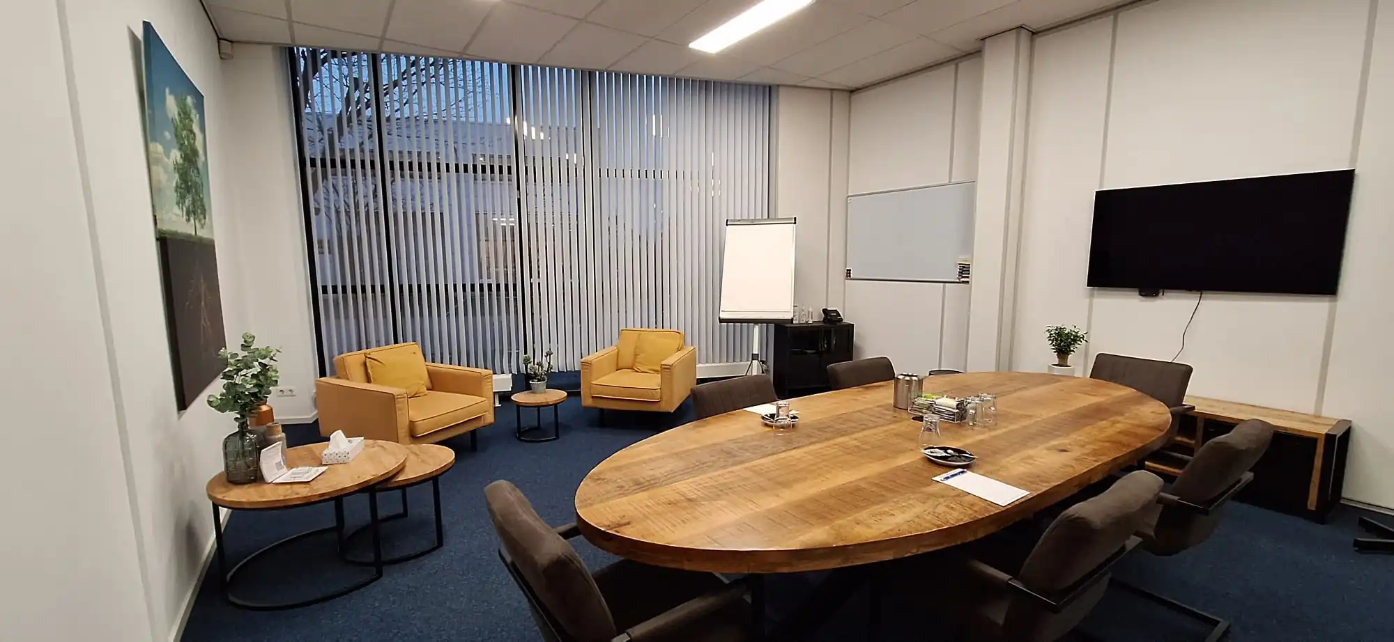 Moderne vergaderruimte aan de Leeghwaterstraat 25 in Reeuwijk met ovale houten tafel, comfortabele stoelen, zithoek en presentatiefaciliteiten.