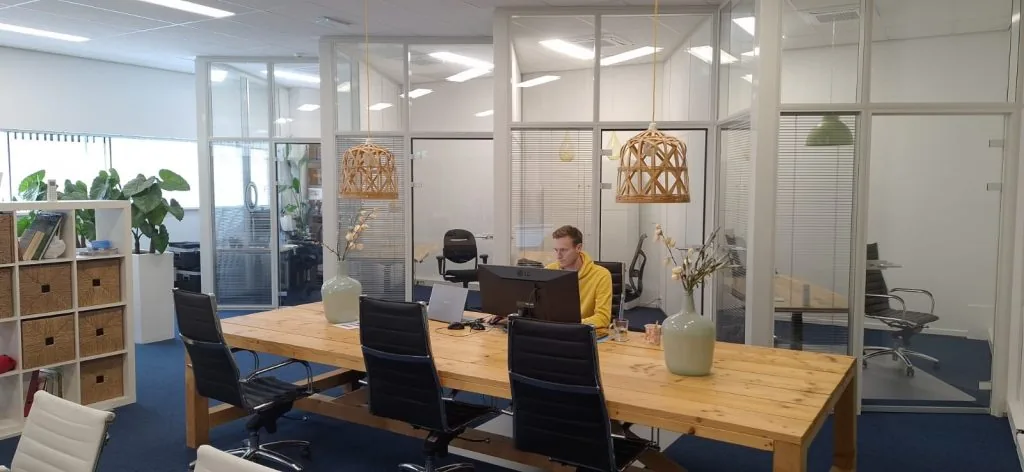 Moderne kantoorruimte aan de Leeghwaterstraat 25 in Reeuwijk met glazen vergaderruimtes, houten vergadertafel en werkplekken.