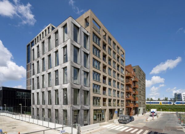 Modern kantoorgebouw op de Oostenburgermiddenstraat met meerdere verdiepingen en grote ramen, gelegen naast een spoorlijn.