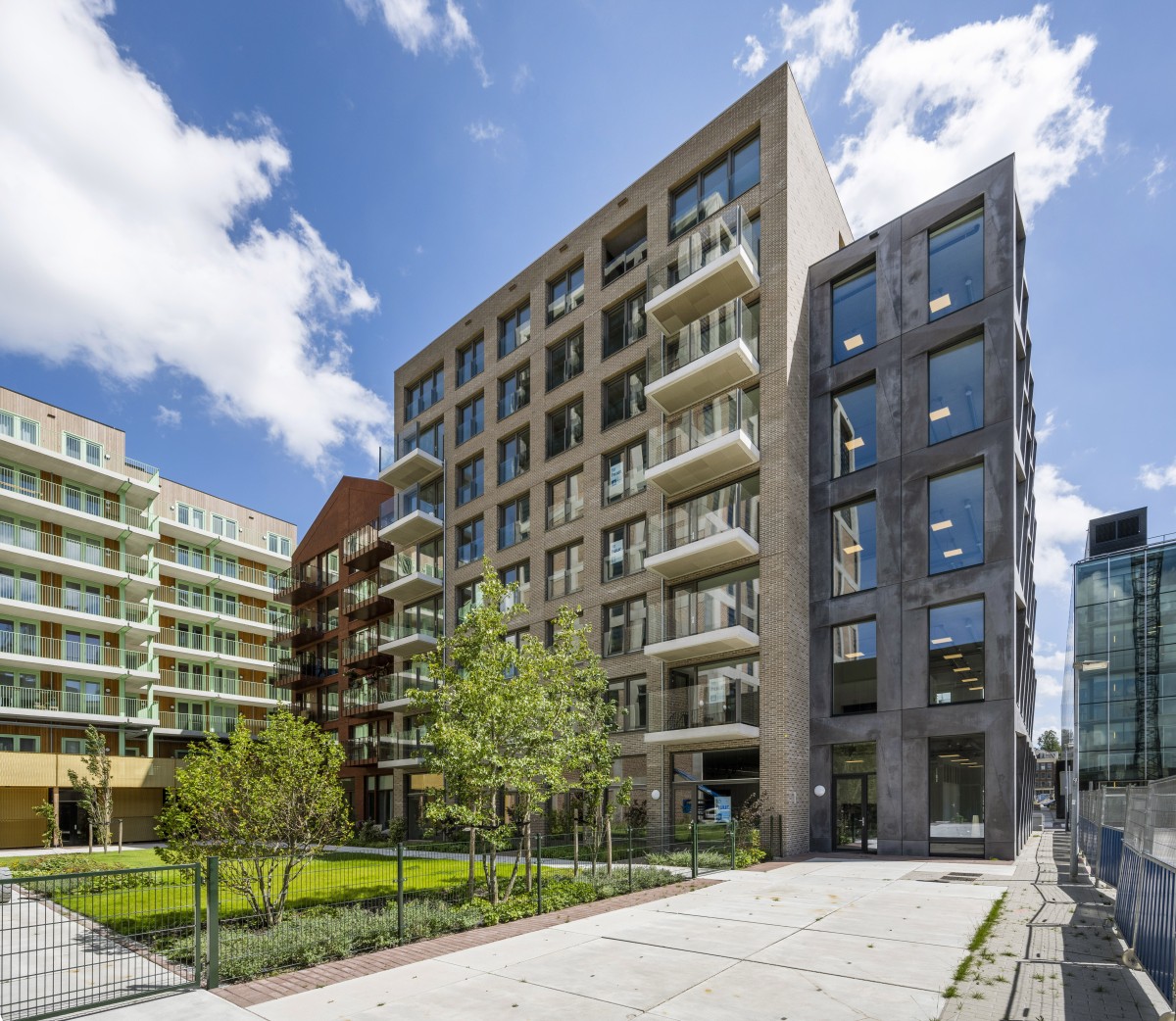 Moderne kantoor- en appartementencomplexen aan de Oostenburgermiddenstraat met een groene tuin ervoor.