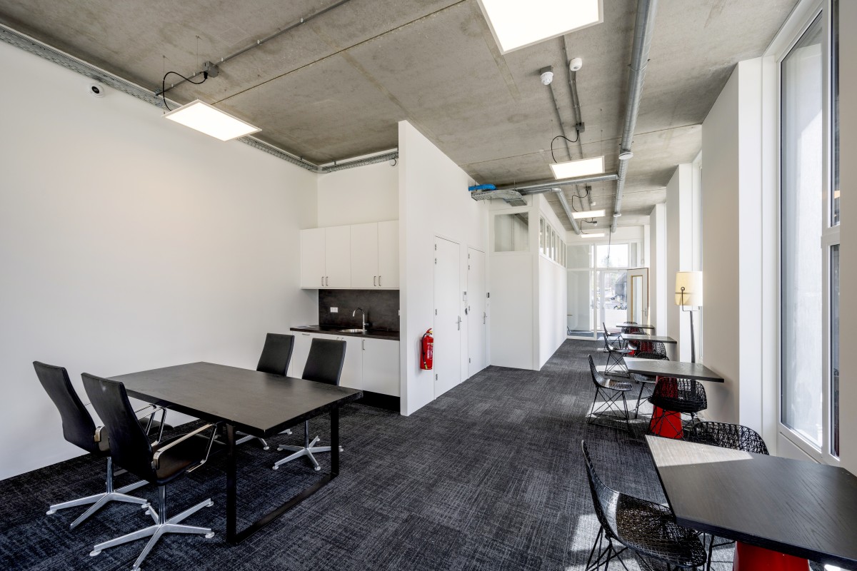 Moderne kantoorruimte met vergadertafels, stoelen en een kitchenette aan de Oostenburgermiddenstraat.